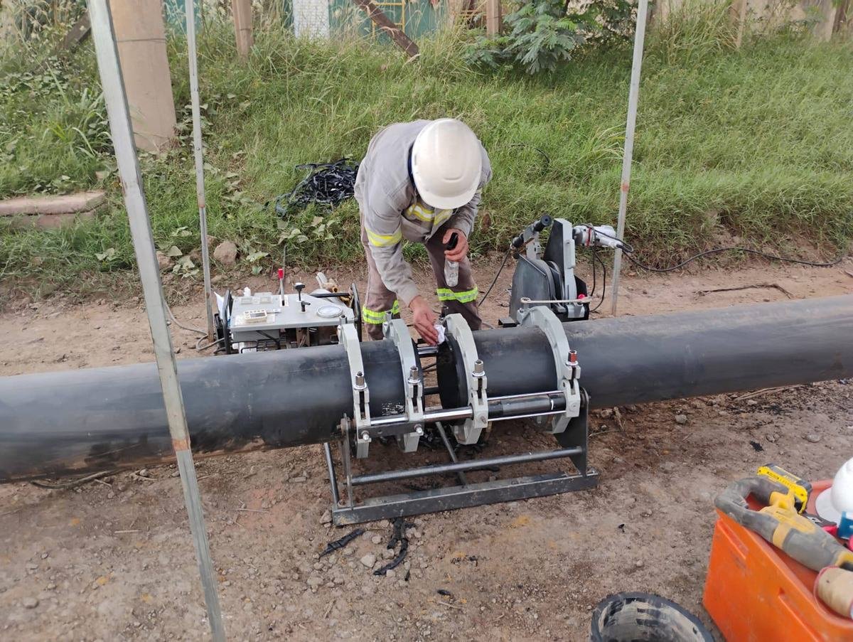 Operador conduzindo solda de topo em tubulação de PEAD com máquina de termofusão